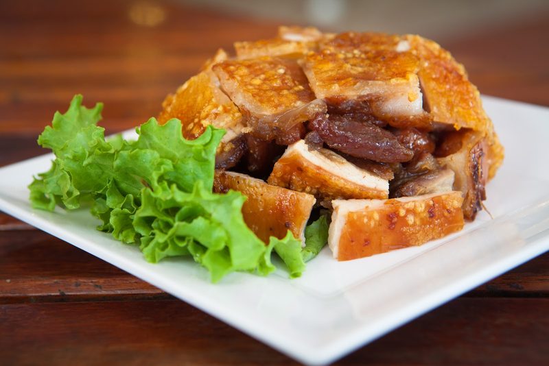 จานหมูย่างของร้าน หนังพองกรอบชั้นหนา วางบนจานขาวกับผักกาดหอม