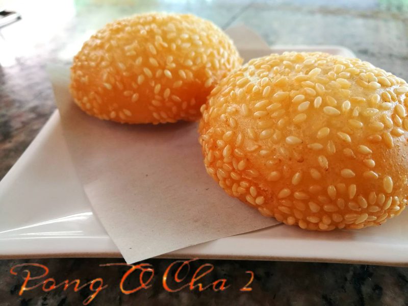 ขนมงาทอดสีทองสองลูกบนจานที่พิมพ์ชื่อ Pong O Cha 2