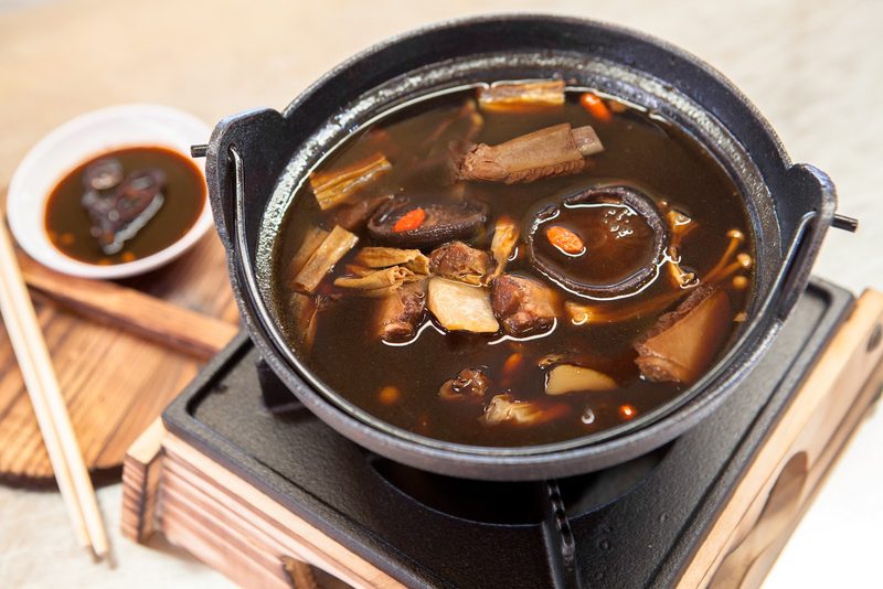บักกุ๊ดเต๋ ซี่โครงหมูในน้ำซุปยาจีนสีเข้ม ในหม้อดำบนเตา