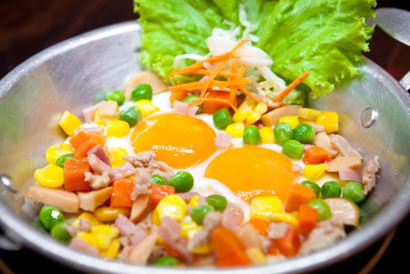 ไข่กระทะ ไข่ดาวในกระทะเล็ก โรยถั่วลันเตา ข้าวโพด แครอท และไส้กรอก
