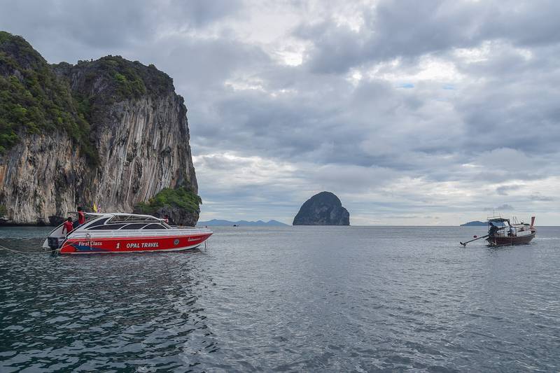 เกาะหินปูนผาสูงกลางทะเล มีเรือเร็วสีแดงแล่นผ่าน